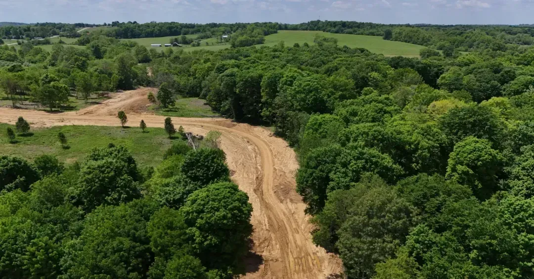An aerial view of a dirt road going through a forest.