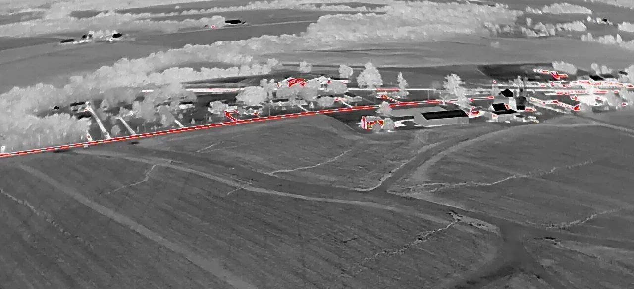 An infra-red aerial view of a farm with a red line going through it.