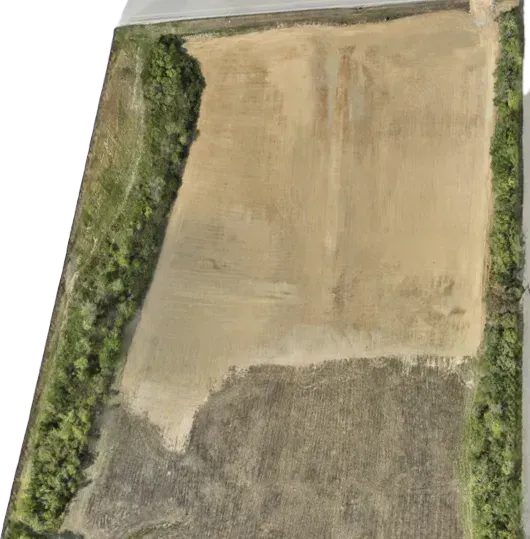 An aerial view of a dirt field surrounded by trees.