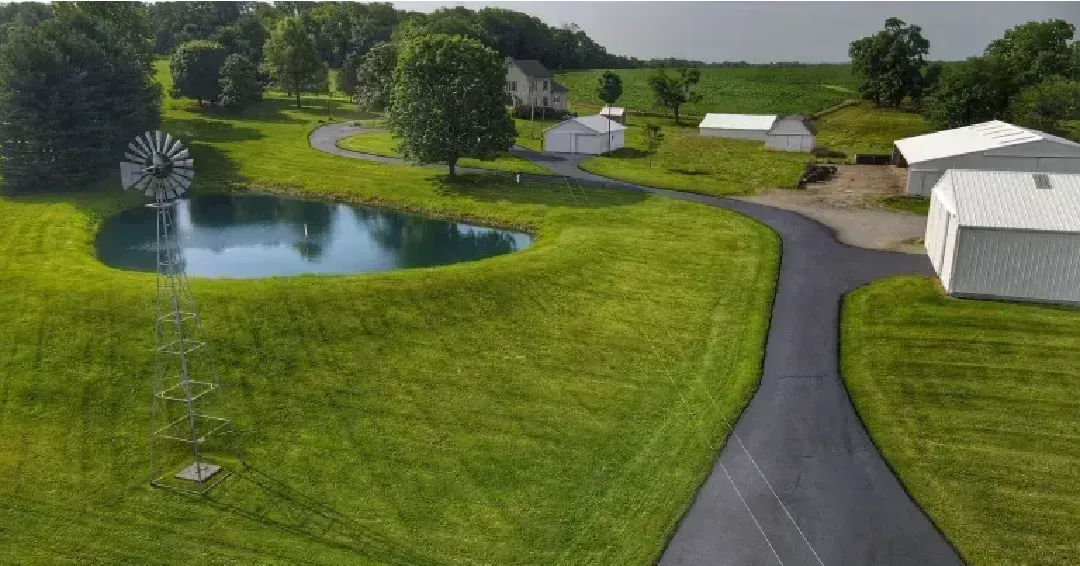 An aerial view of a farm with a pond and a windmill.