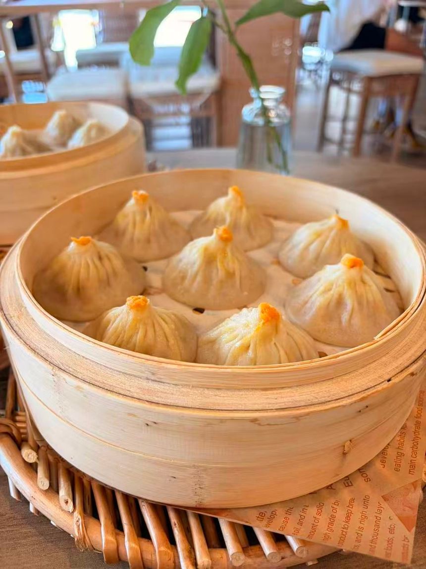 Bowl of spicy noodles topped with minced meat and green onions on a wooden table