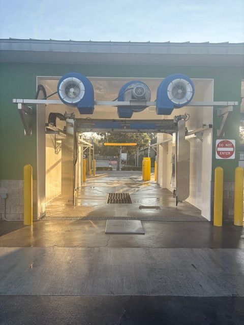 Car wash entrance with blue fans and yellow safety poles.