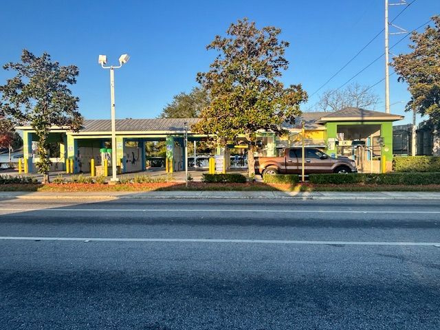 Car wash with green accents and a brown pickup truck. Located near a street.