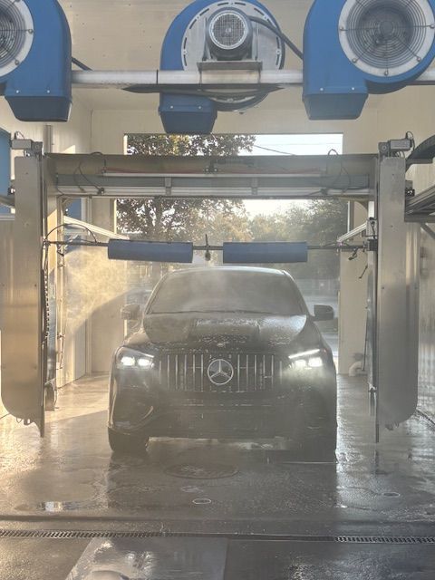 Car in a car wash, surrounded by blue brushes and spraying water, covered in foam. Car in a car wash, surrounded by blue brushes and spraying water, covered in foam.