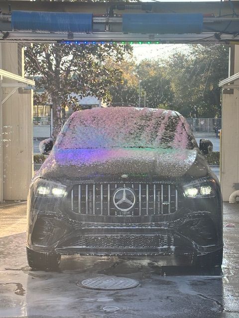 Silver SUV exiting car wash; blue bubble decor on the walls, sunlit. Silver SUV exiting car wash; blue bubble decor on the walls, sunlit.