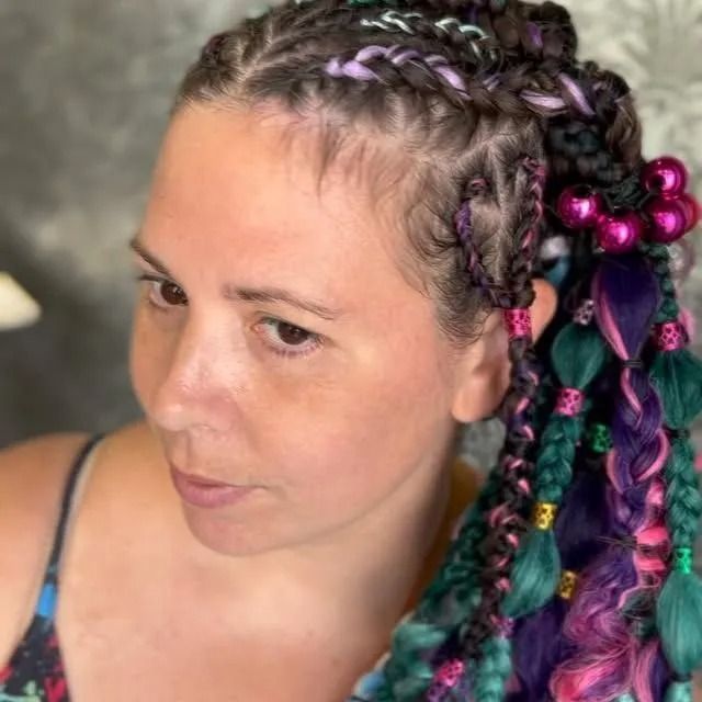 Close-up of a woman with purple braided hair and colorful beaded accents, looking down