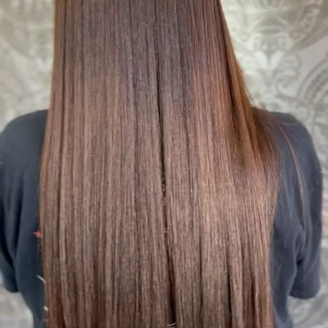Long, straight brown hair seen from behind against a patterned gray background