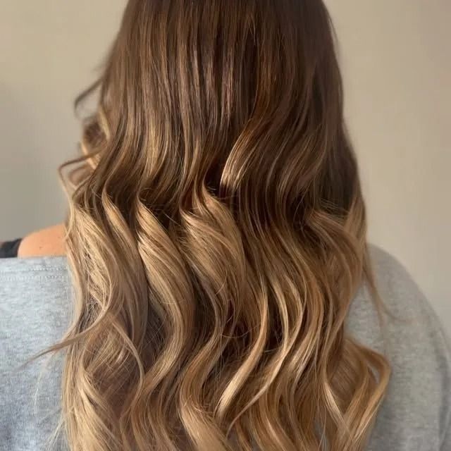 Wavy shoulder-length hair with blonde highlights against a gray shirt and neutral background