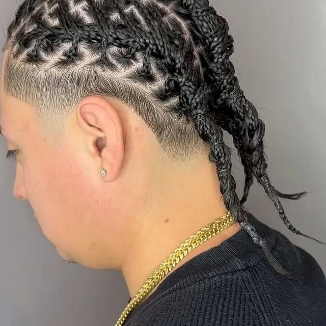 Braided hairstyle with cornrows on the sides and long braids tied back, shown in profile on a gray background