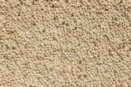 Close-up of beige, textured sand or gravel surface.
