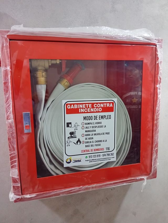 Armario rojo para mangueras contra incendios con manguera enrollada y frontal de cristal etiquetado, montado en la pared.