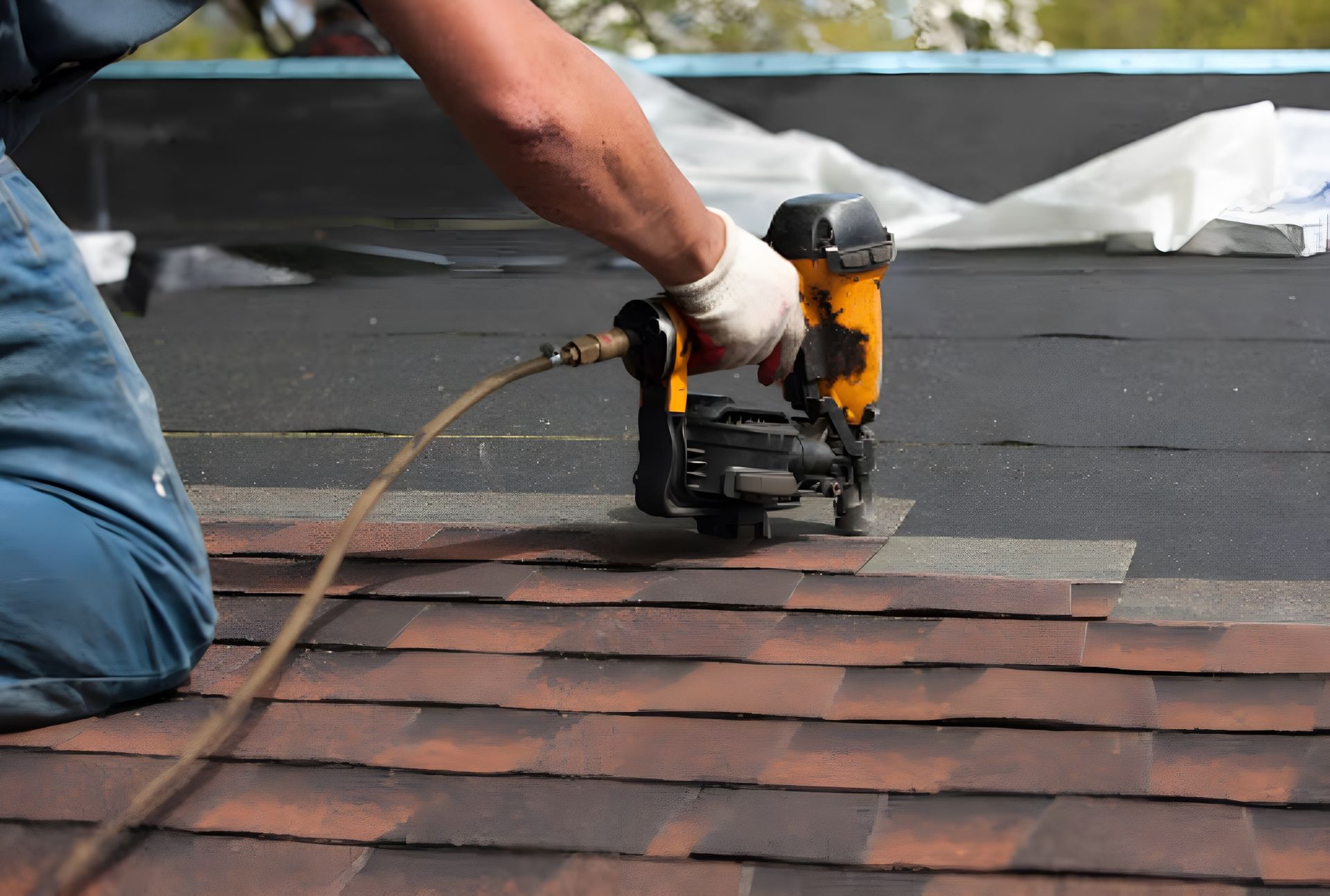 Man with a nail gun nailing tiles on a roof— Roofing Gold Coast in Tallebudgera, QLD