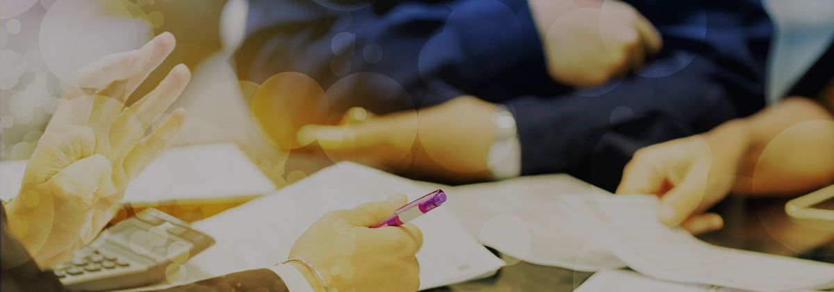 Hands reaching toward papers and envelopes spread across a table in a meeting or brainstorming session