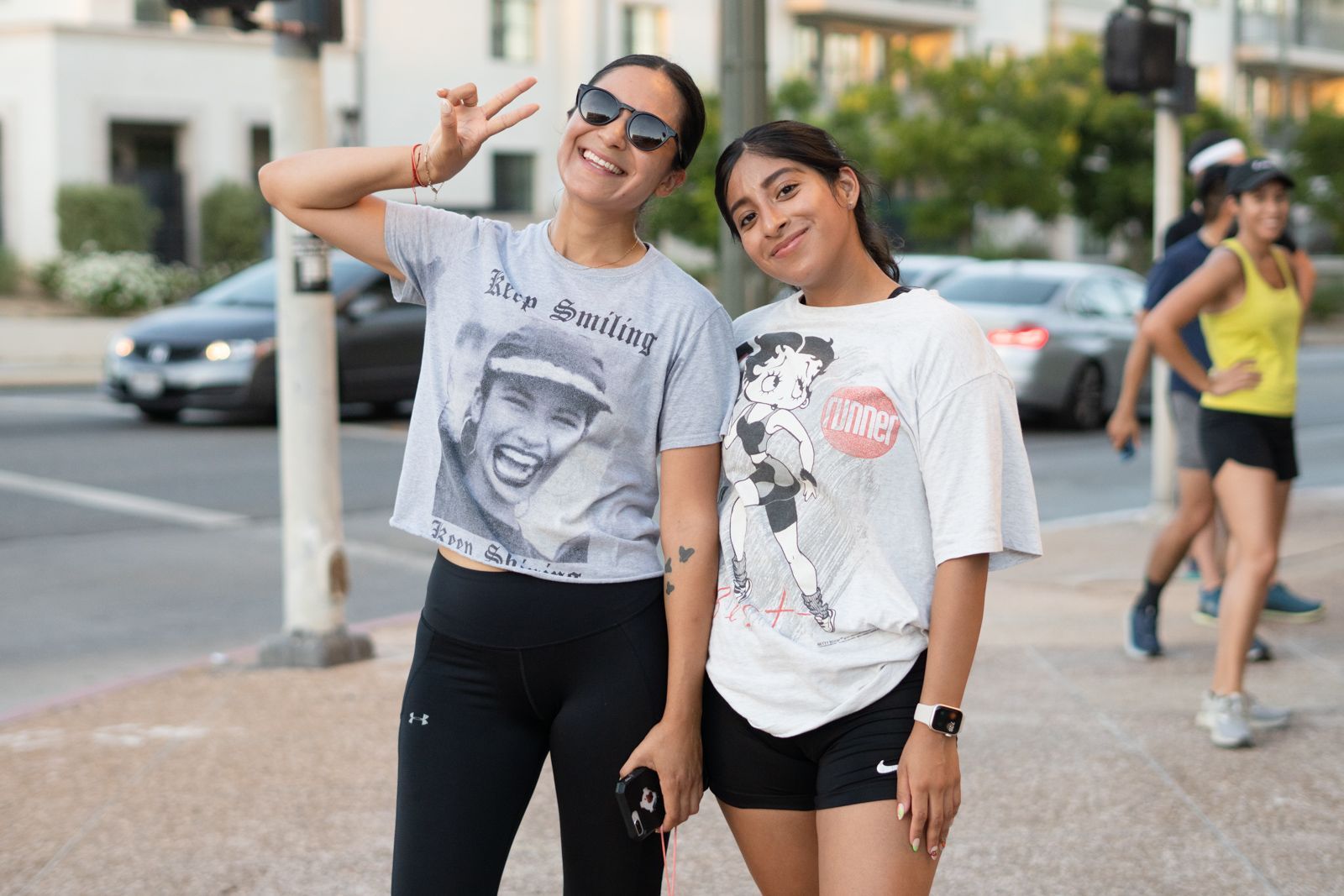 Two women are standing next to each other on a sidewalk.