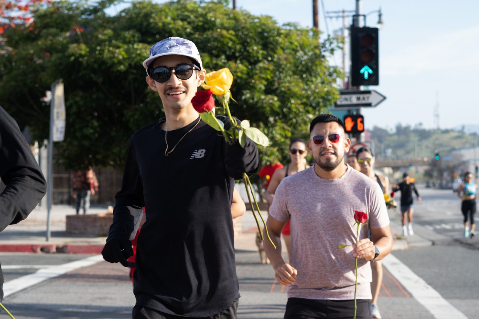 A group of men are walking down the street holding roses.