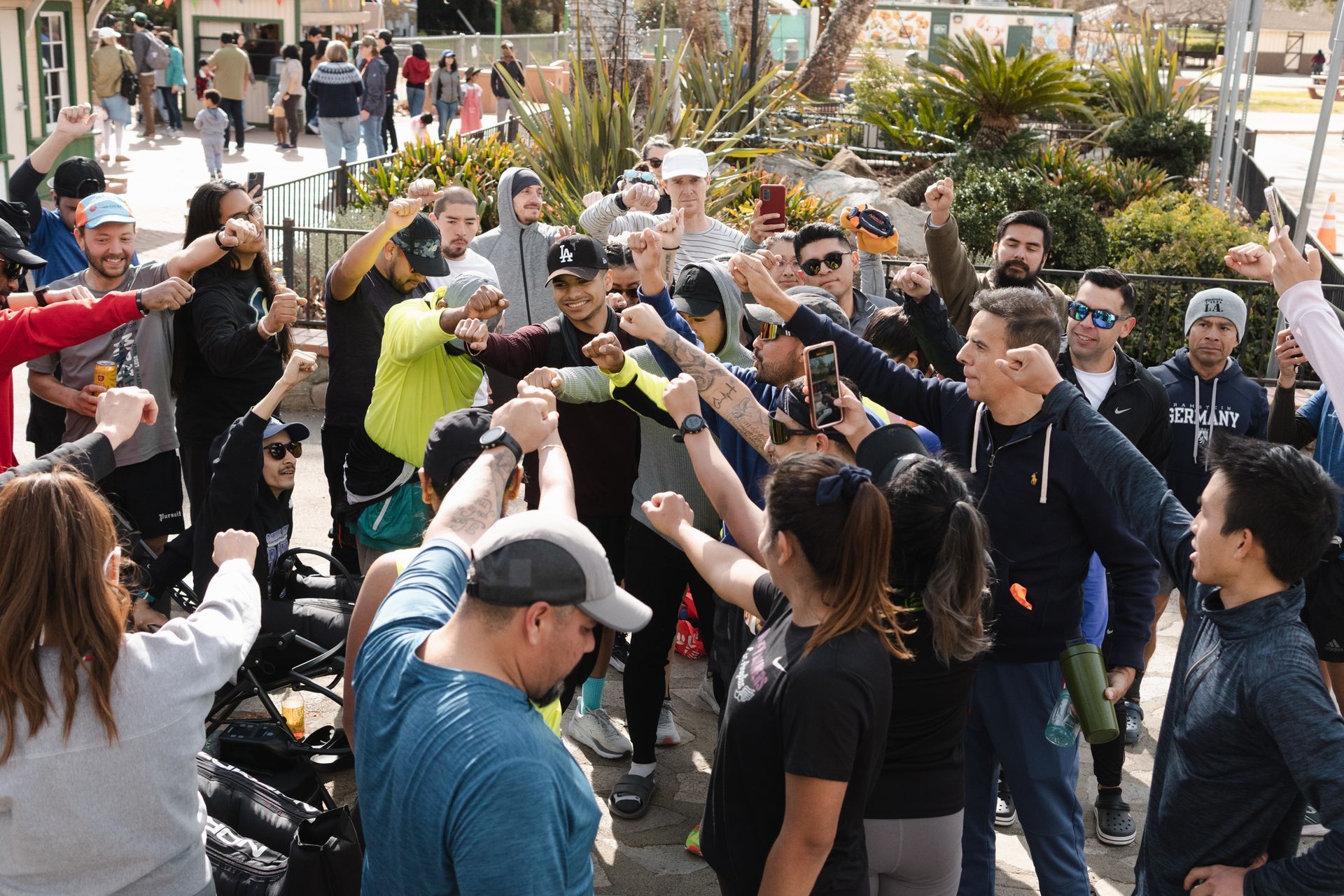 A large group of people are standing in a circle with their fists in the air.