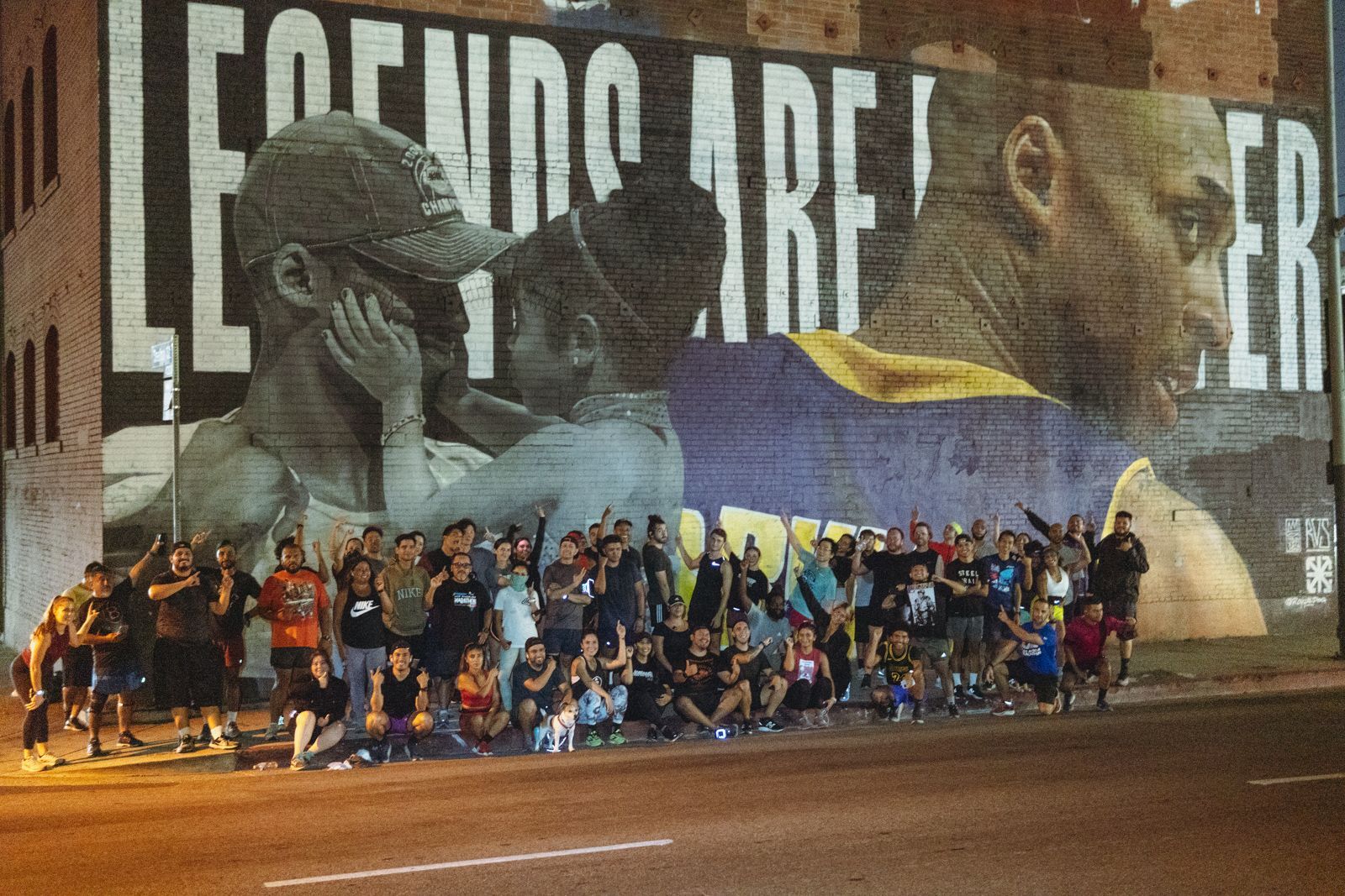 A group of people standing in front of a mural that says legends are