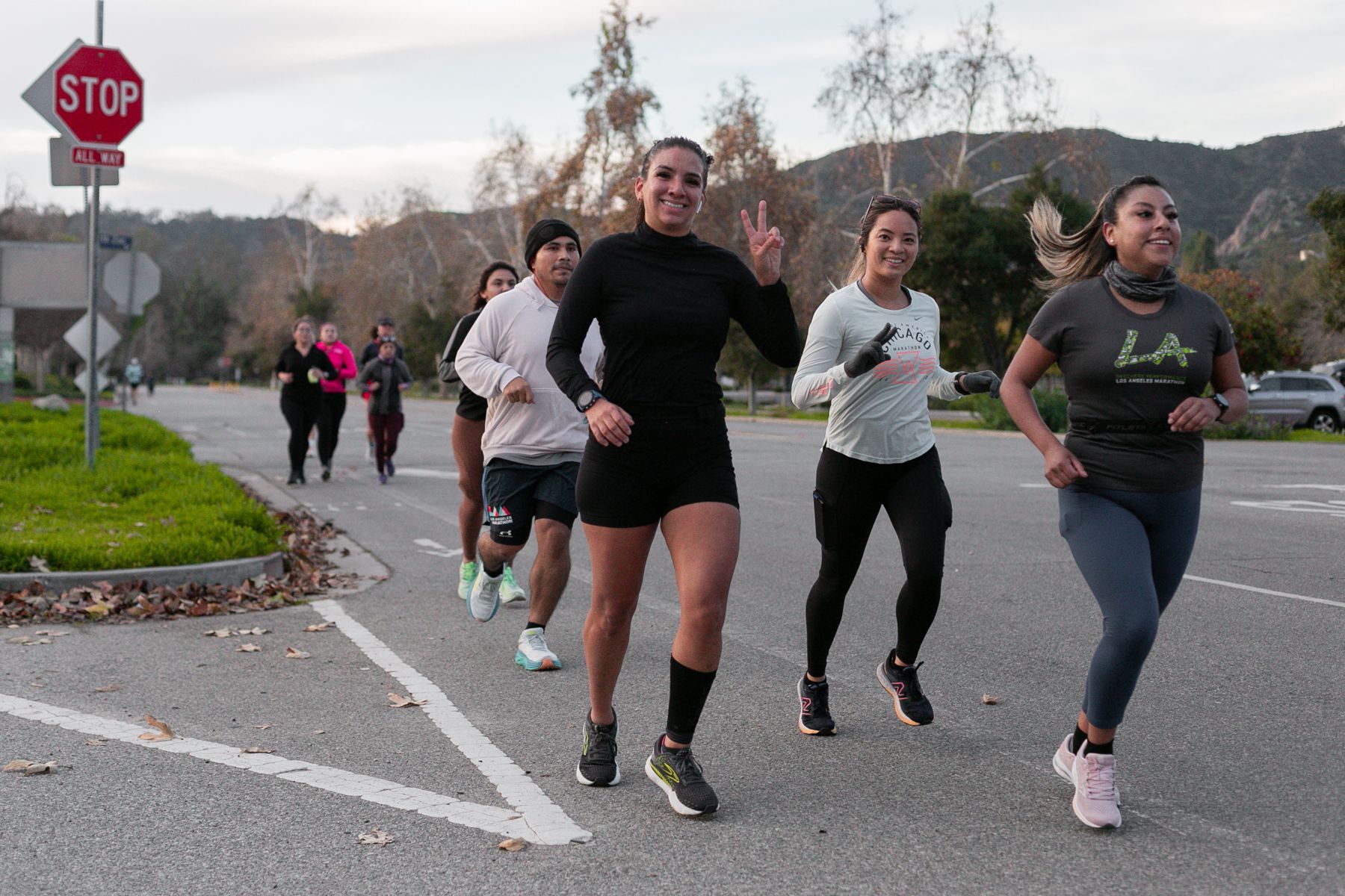 A group of people are running down a street in front of a stop sign.