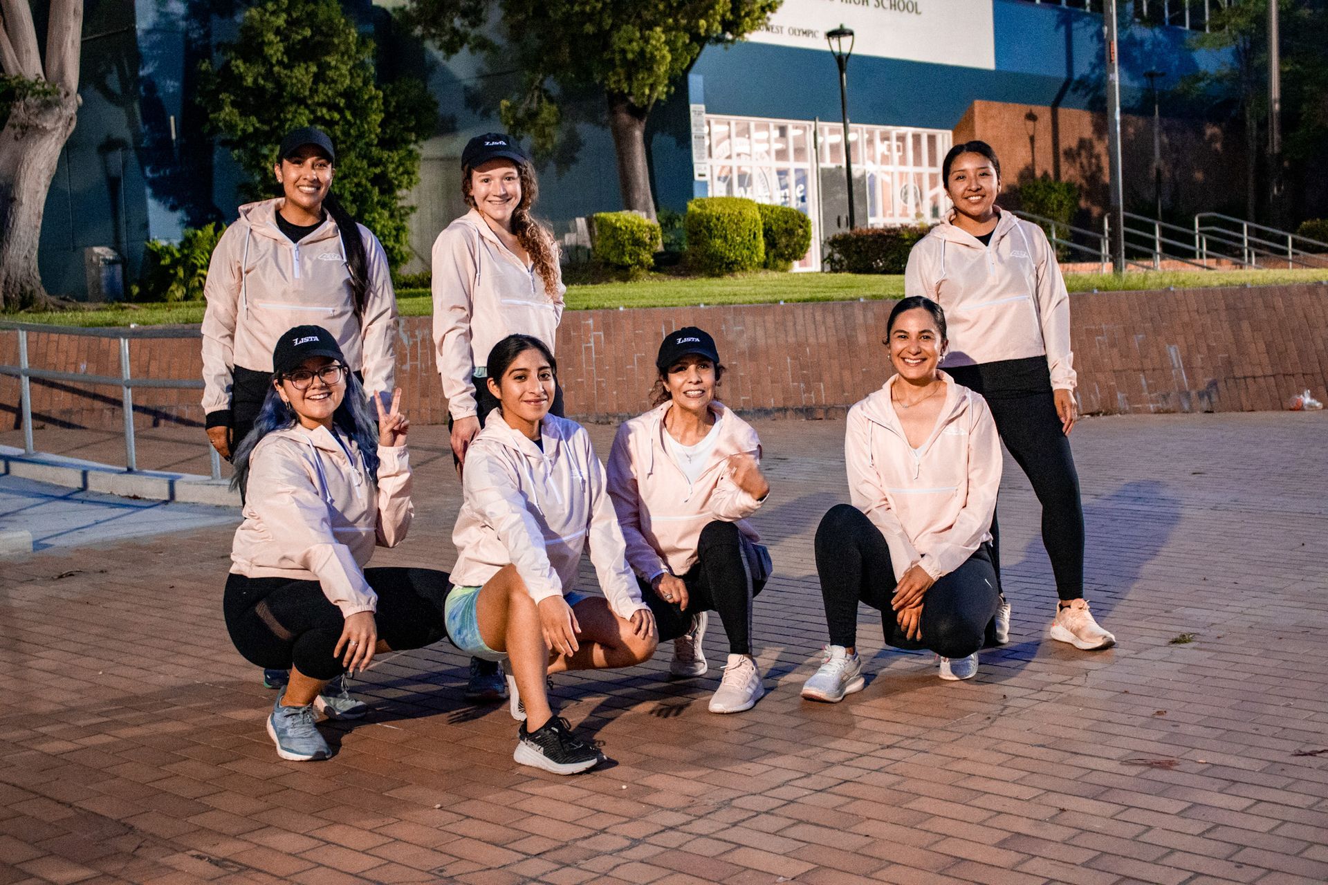 A group of women are posing for a picture on a sidewalk.