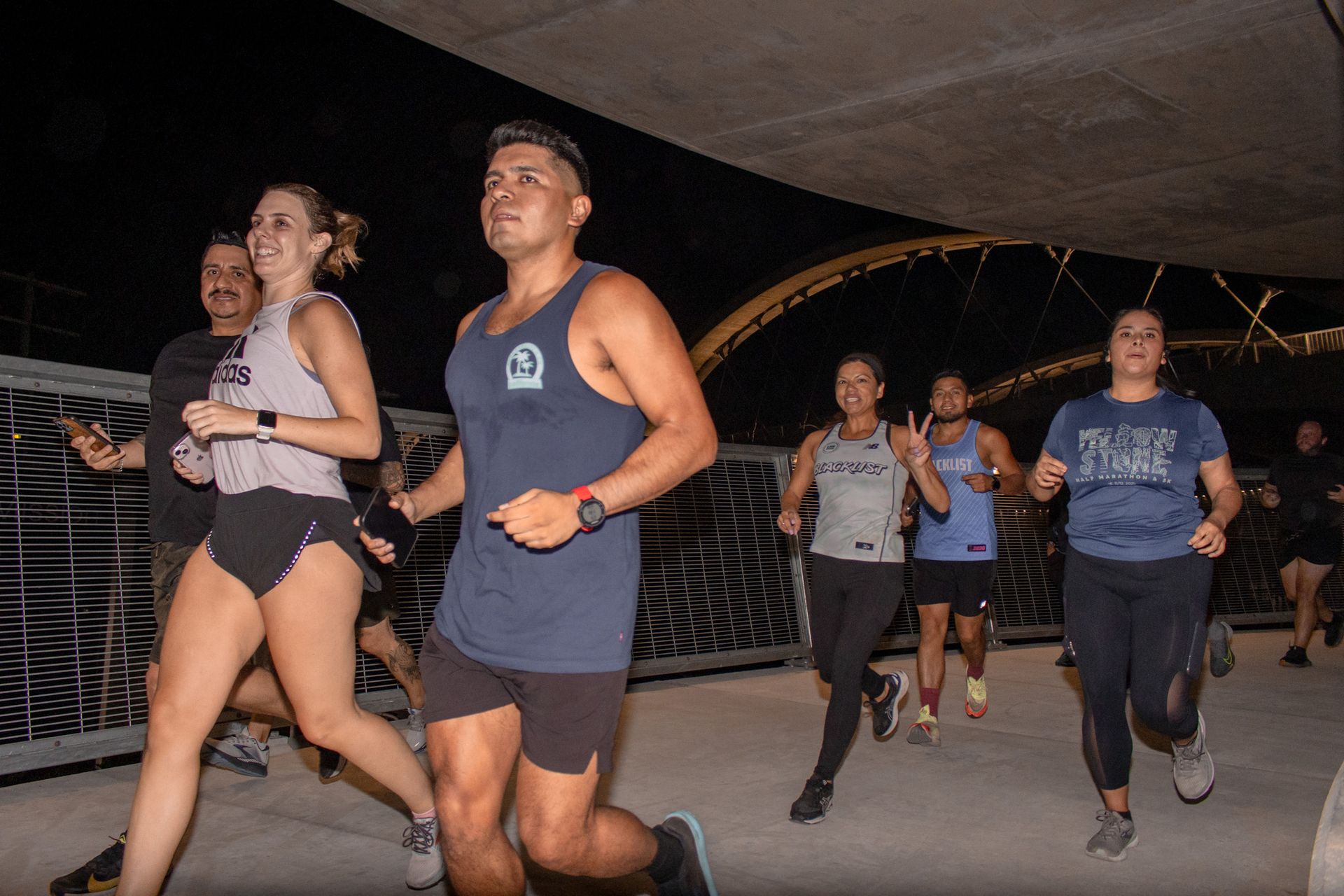 A group of people are running on a bridge at night.