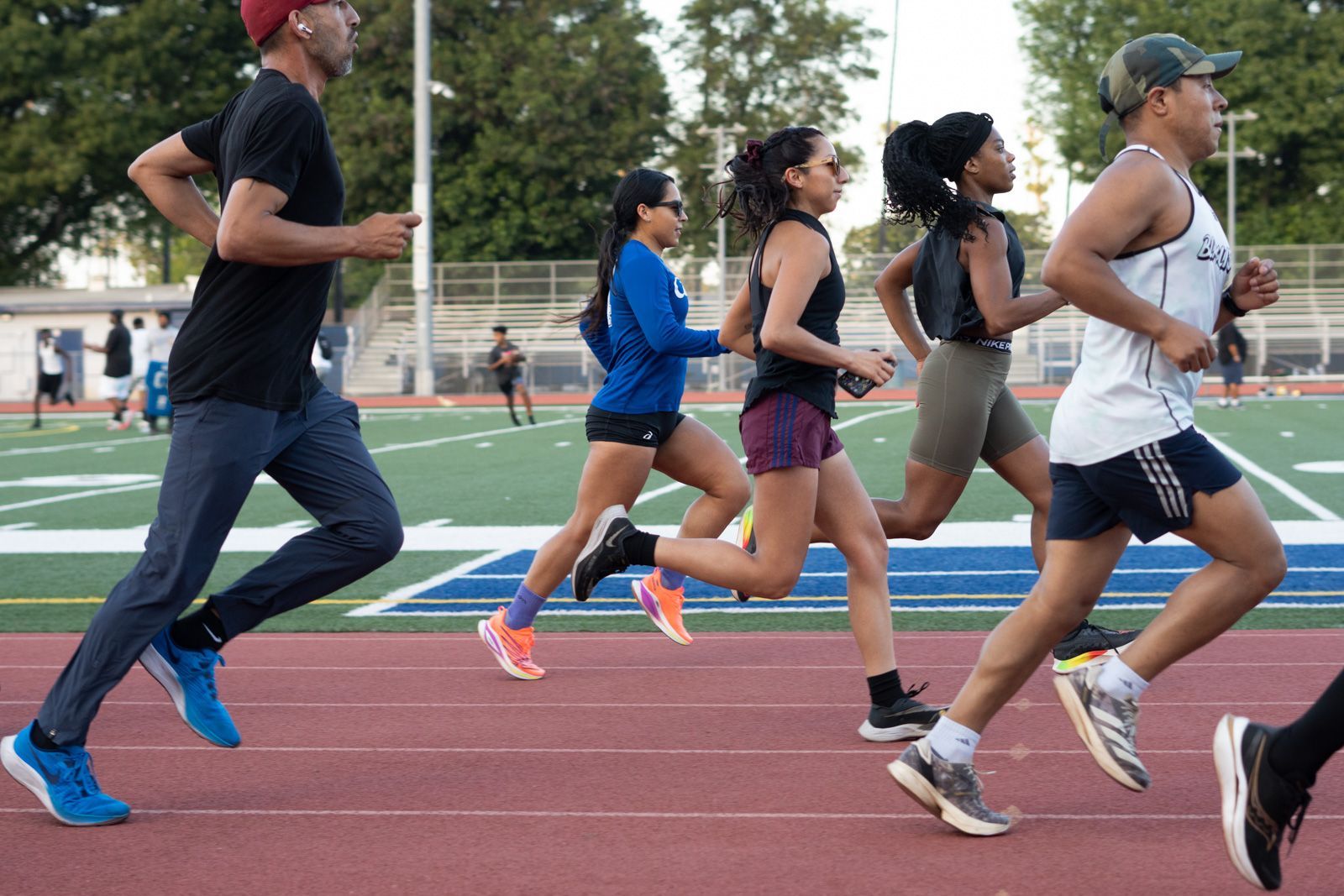 Group of runners striding in harmony at an outdoor track during BlacklistLA's community workout