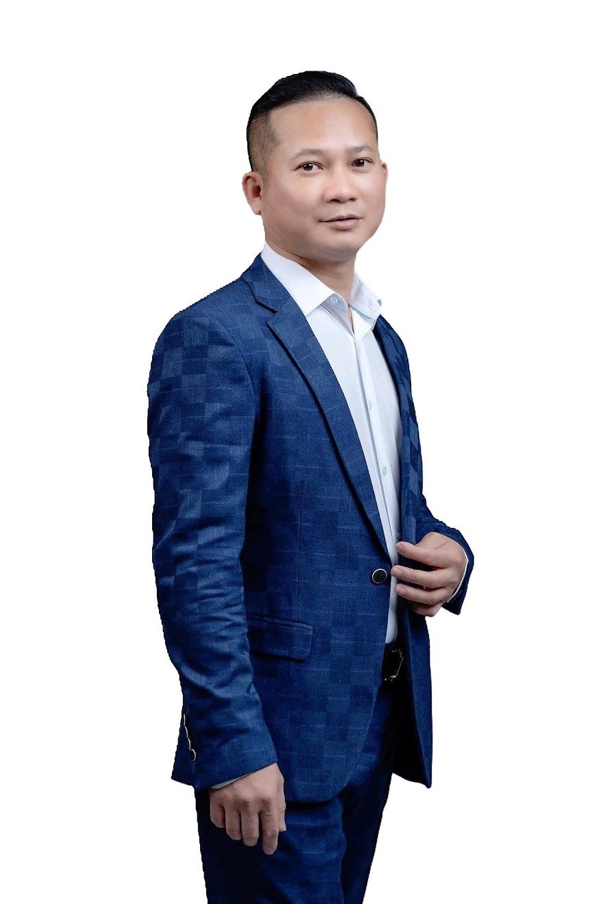 A person wearing a patterned blue suit jacket and white button-down shirt, facing slightly to the side against white.