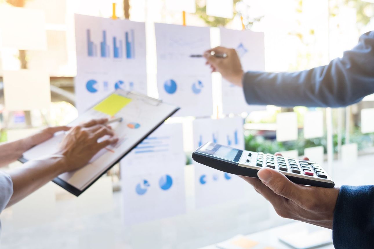 People reviewing charts and a calculator in a bright office meeting