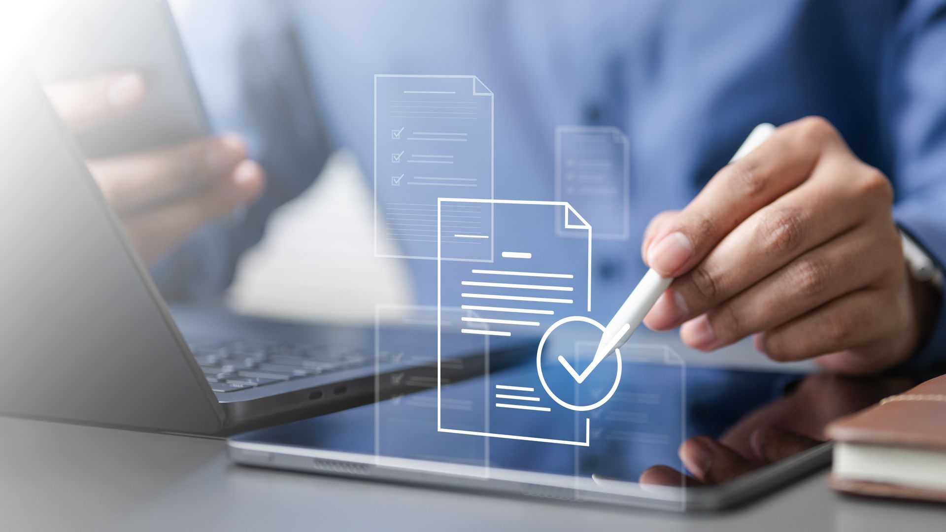 Hand checking documents beside a laptop, with a glowing digital checklist overlay
