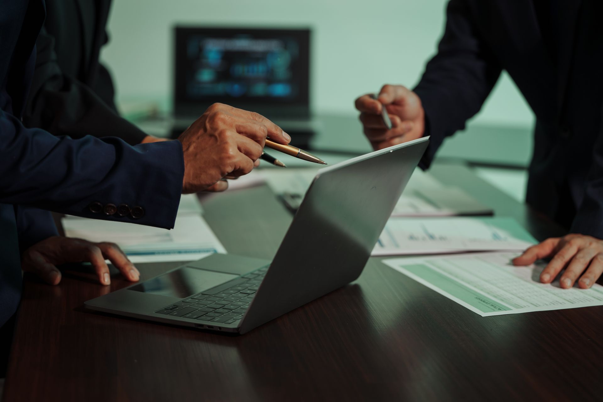 People reviewing documents around an open laptop on a conference table