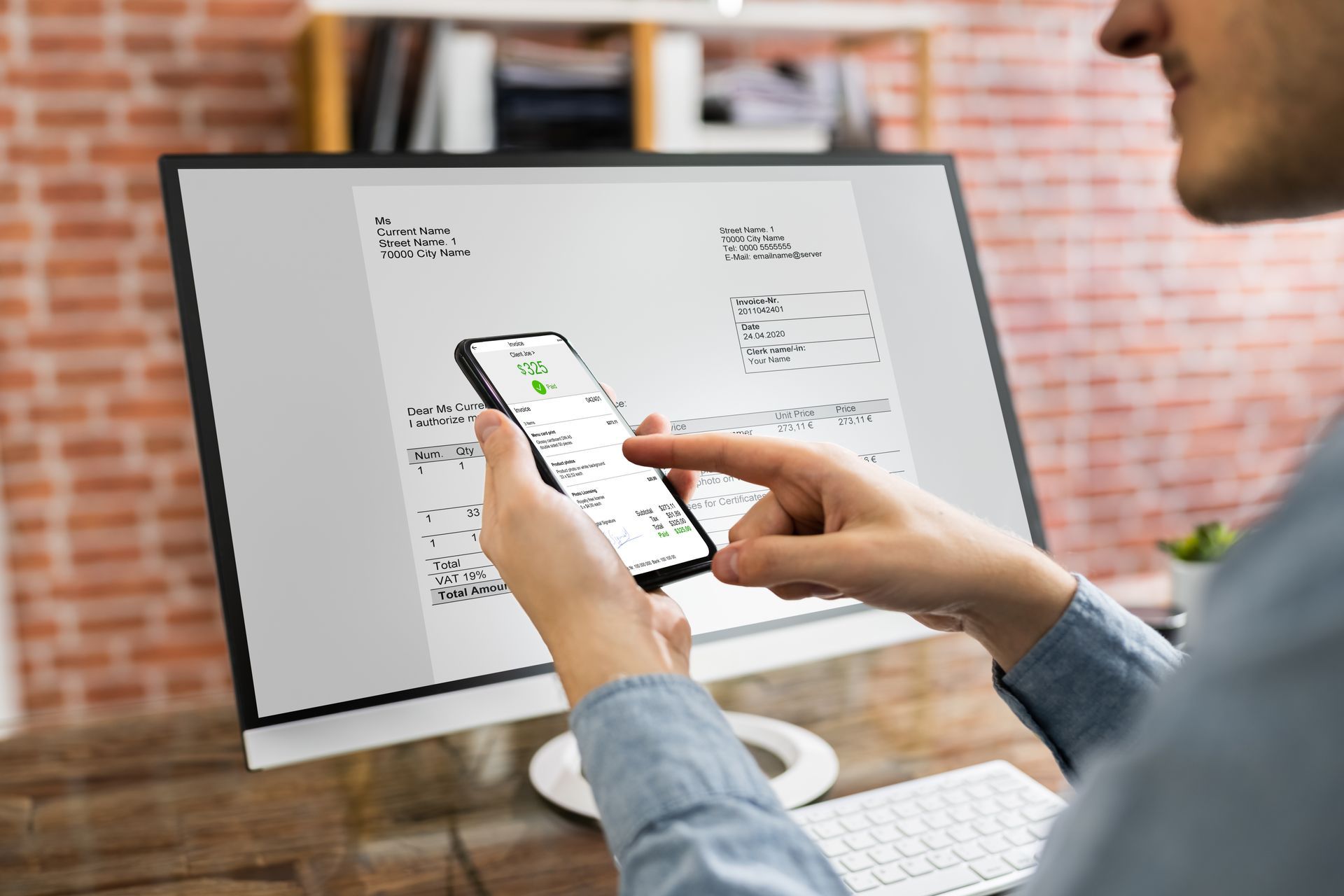 Person using a smartphone in front of a desktop monitor with wireframe sketches on screen
