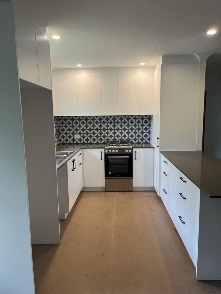 An Empty Kitchen With White Cabinets and Stainless Steel Appliances — D Hinged Kitchens & Joinery in Main Arm, NSW