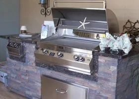 a stainless steel grill is sitting on top of a brick counter