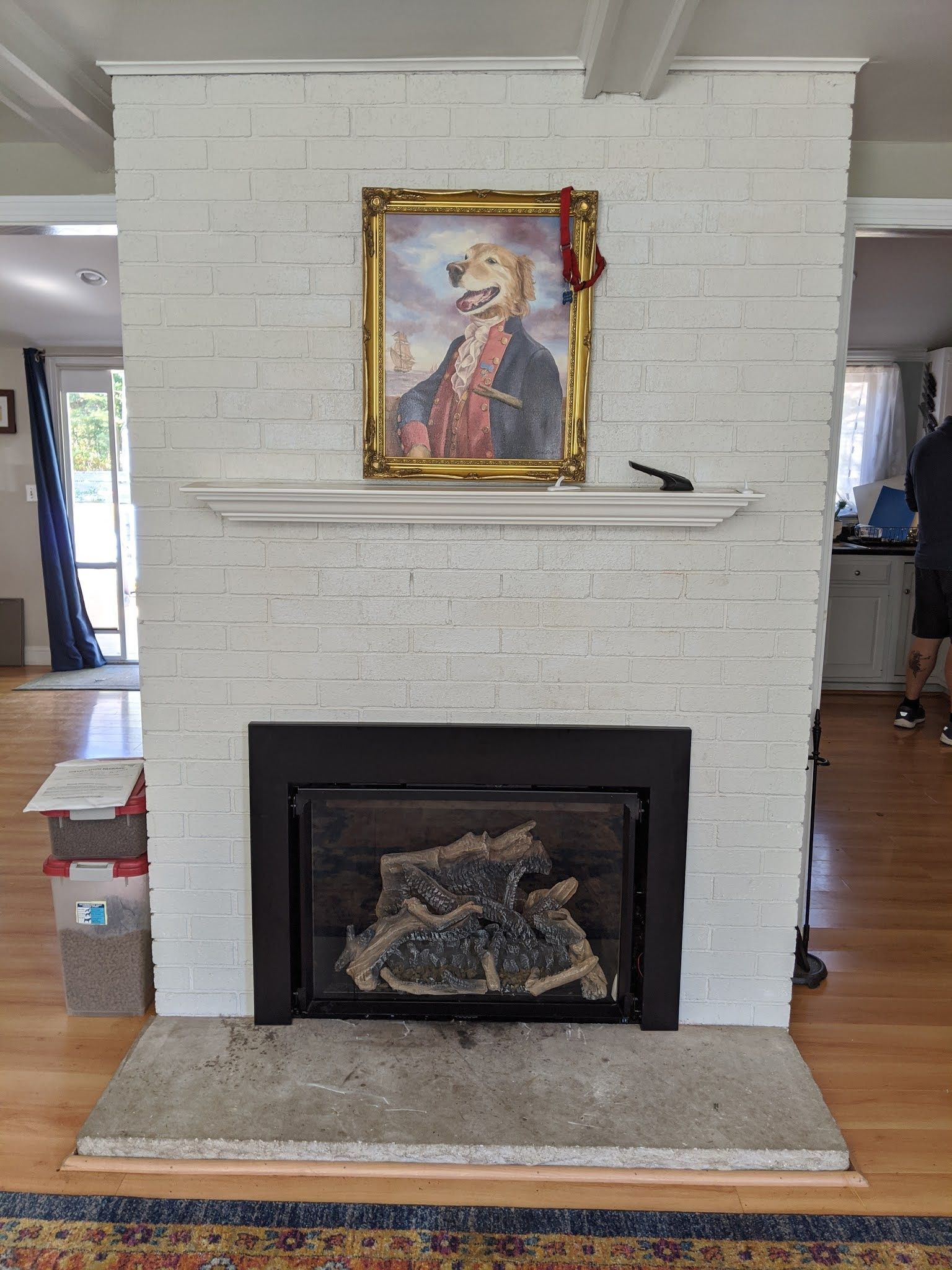 A white brick fireplace with a picture of a dog on the mantle.