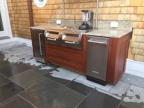 A kitchen with stainless steel appliances and wooden cabinets on a tiled floor.