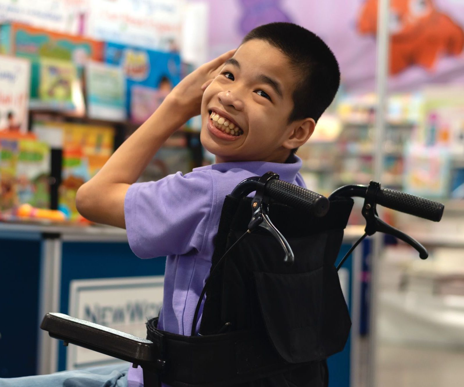 A young boy in a wheelchair is smiling while at school.