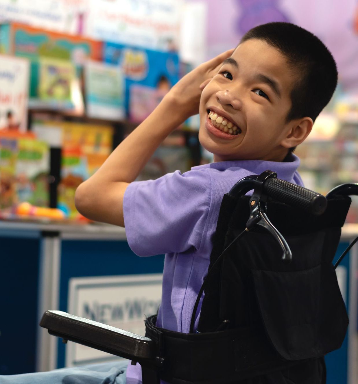 A young boy in a wheelchair is smiling while at school.