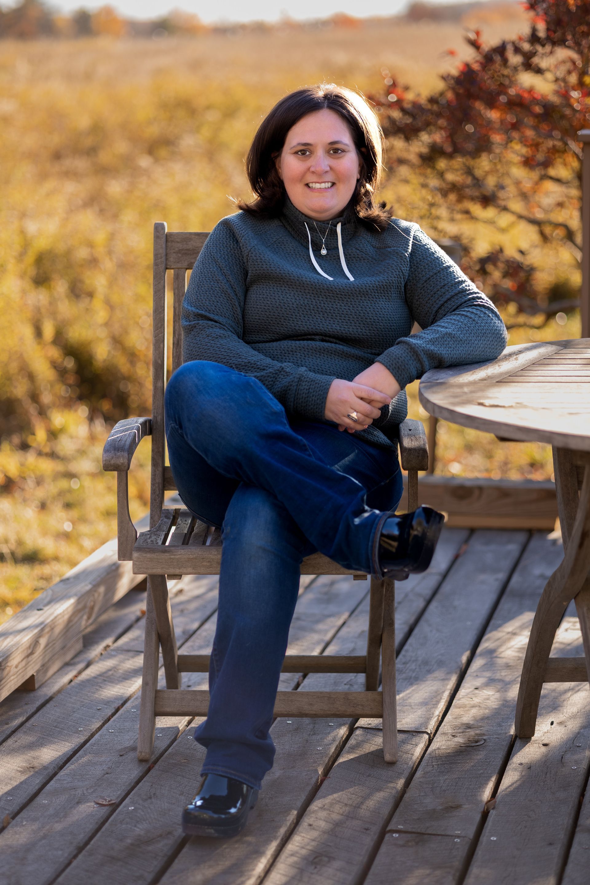 Owner Samantha wearing a green shirt and a hat is holding binoculars while in the mountains.
