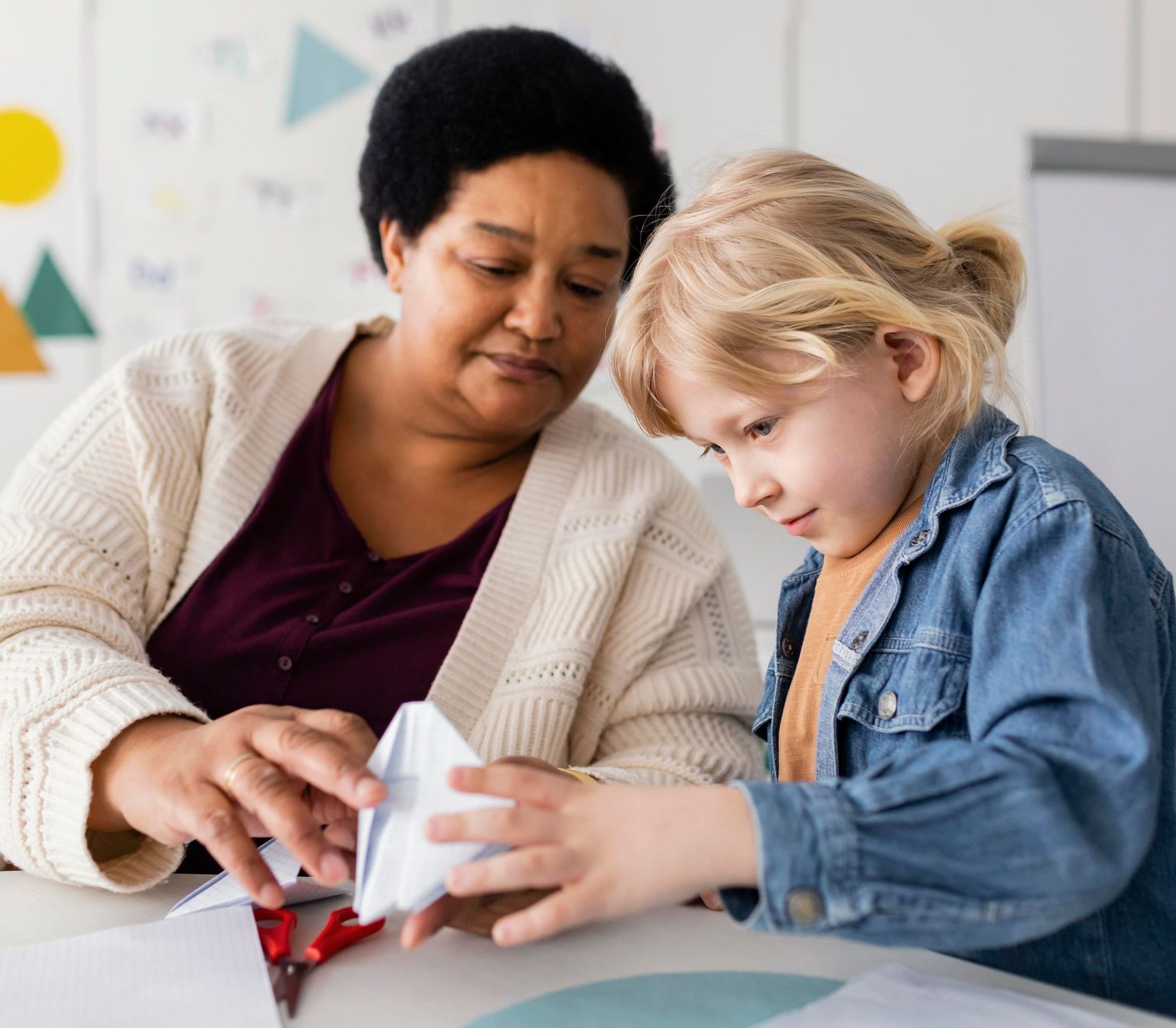 Young woman with glasses working with a small boy playing with wooden toys