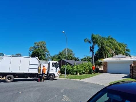 A garbage truck is parked on the side of the road in front of a house.