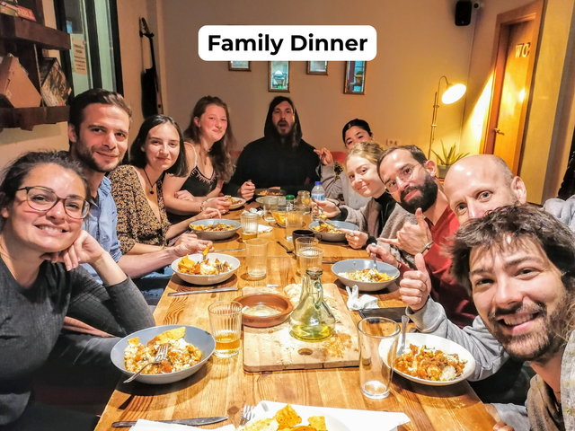 Group of friends sharing a dinner around a long table in a cozy restaurant, smiling at the camera.