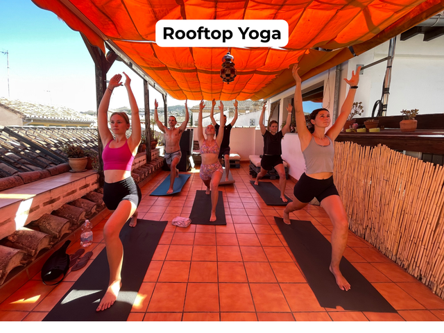 People doing yoga on a rooftop under orange canopy, with “Rooftop Yoga” sign above.