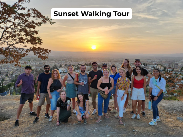 Group posing at sunset on a walking tour, with a “Sunset Walking Tour” label and city view behind them