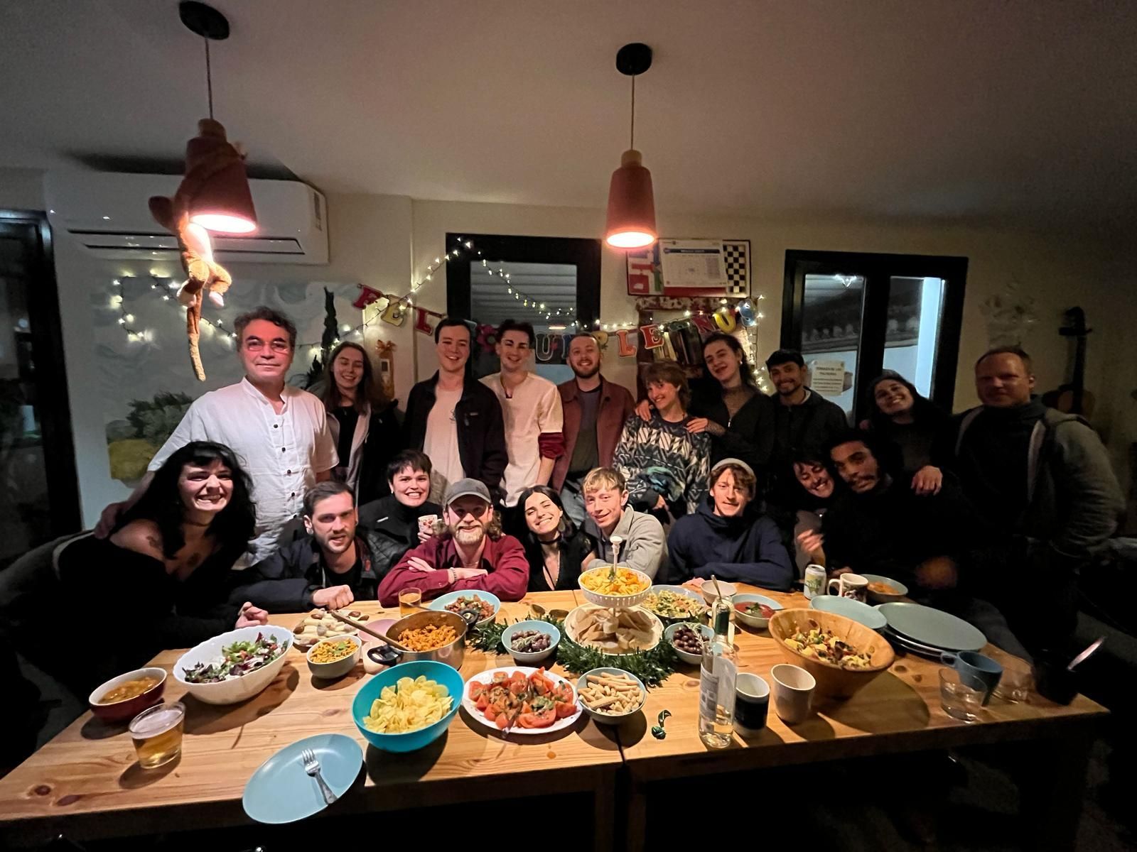 Group of people gathered around a table full of food at a warm indoor celebration