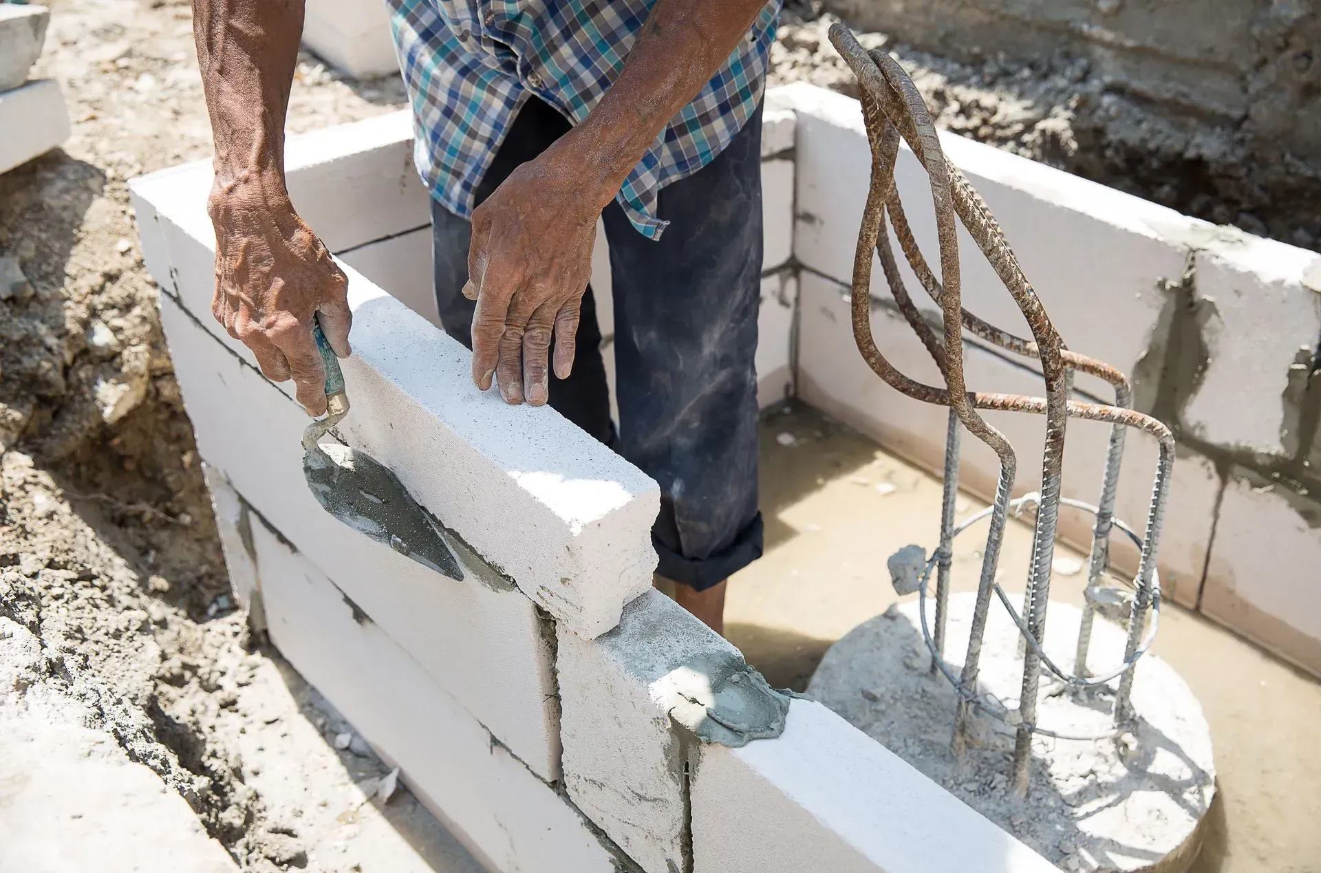 A man is laying bricks on a construction site.