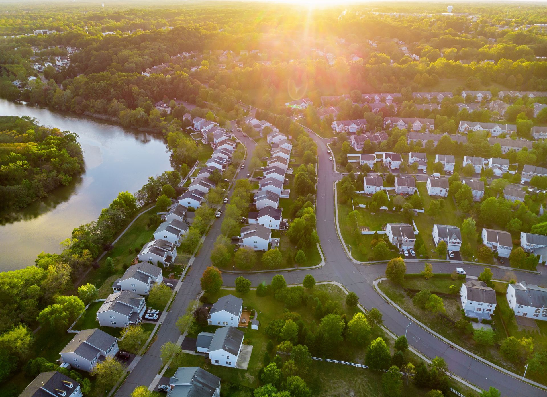 Aerial view of a suburban neighborhood beside a winding river at sunset