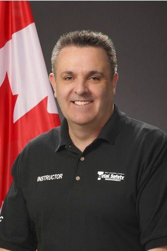 A man in a black shirt is smiling in front of a canadian flag