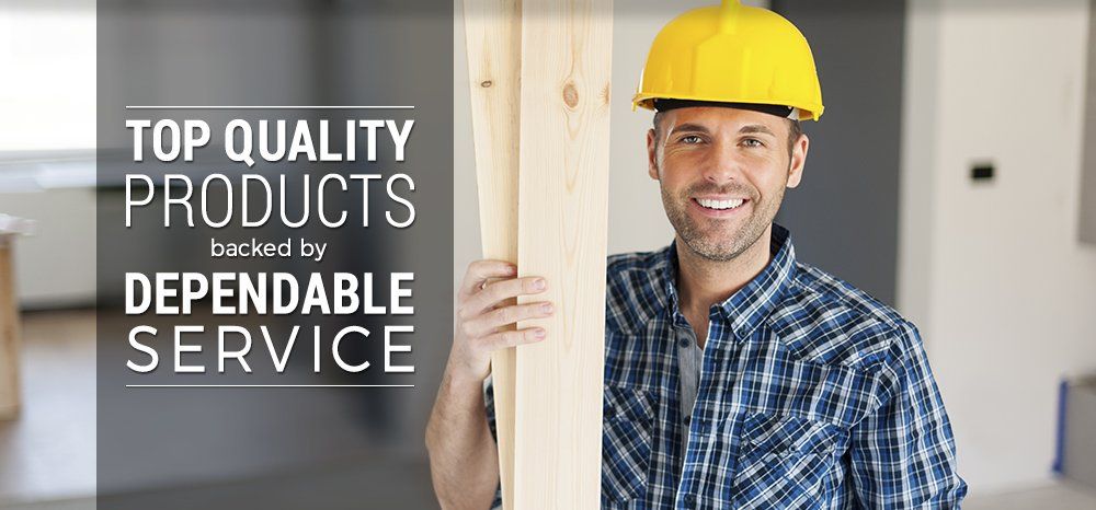 A man wearing a hard hat is holding a piece of wood.