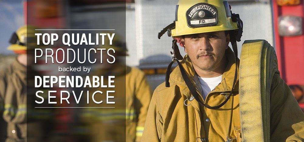 A fireman wearing a yellow helmet and carrying a hose.