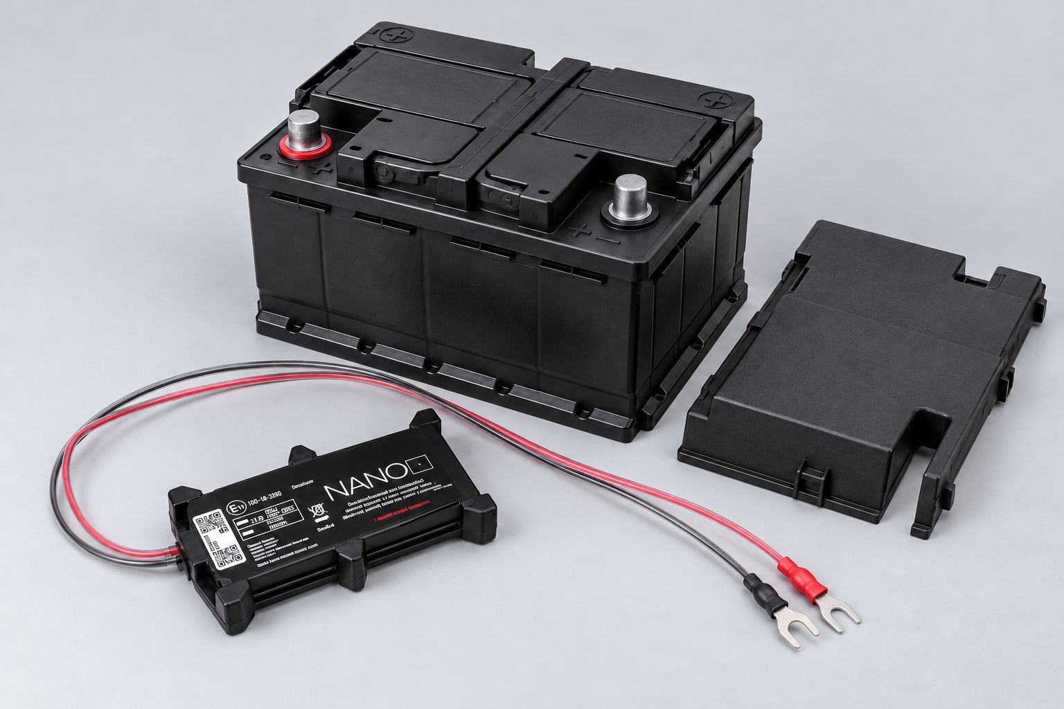 AGL Nano tracker positioned beside a vehicle battery with cables ready for installation.