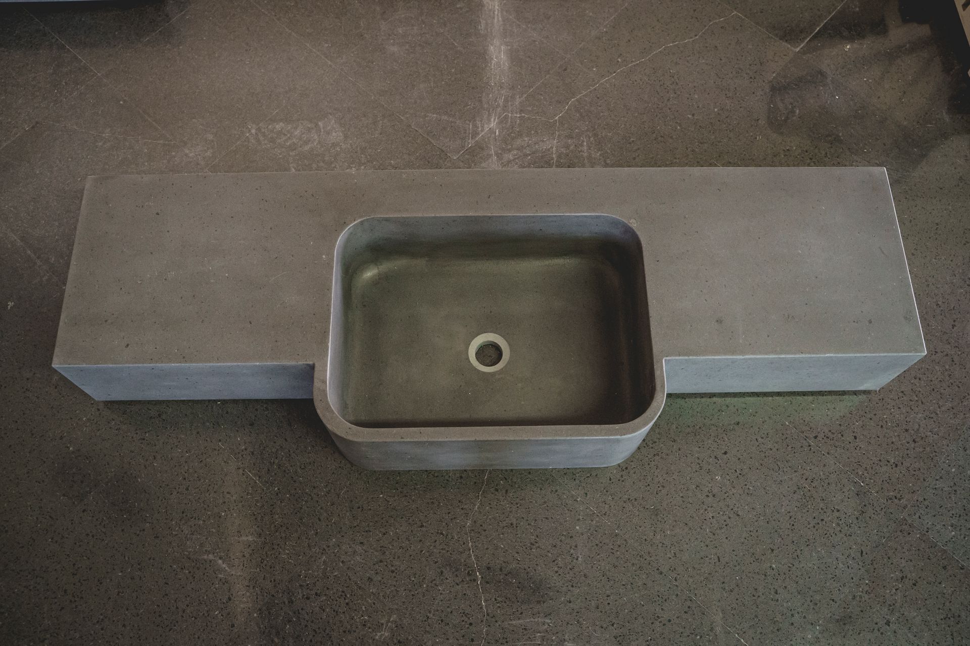 Piano del bagno in cemento grigio con lavabo integrato.